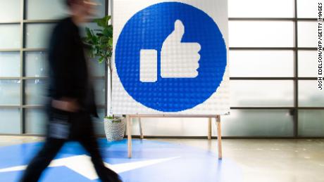 A Facebook employee walks by a sign displaying the &quot;like&quot; sign at Facebook&#39;s corporate headquarters campus in Menlo Park, California, on October 23, 2019. (Photo by Josh Edelson/AFP/Getty Images