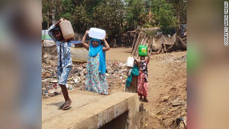 Residents carrying boxes of water in Ambedkar Nagar’s slum in Mumbai, India in 2021.
