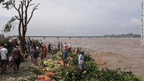 People stand along the banks of the flooded Karnali River following heavy rains in Rajapur village of Bardiya district in Nepal on October 20.
