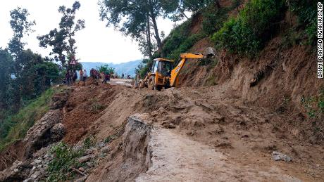 Workers clear a road hit by a landslide in Dipayal Silgadhi, Nepal, on Thursday.