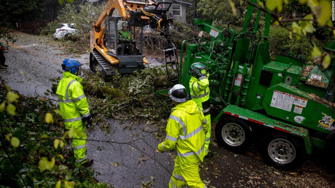 Workers clear branches from a road in Forestville, California, on Sunday.