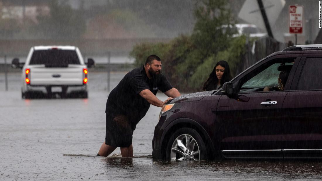 A couple pushes a vehicle away from a flooded area in Fairfield, California, on Sunday.