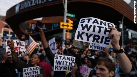 Protesters rallying against COVID-19 vaccination mandates and in support of Kyrie Irving gather in the street outside the Barclays Center.