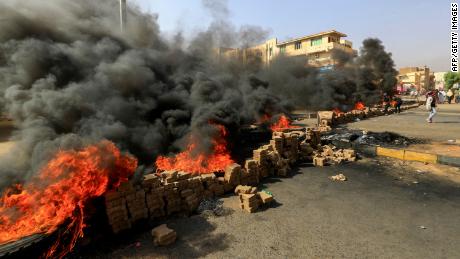 Sudanese protesters use bricks and burn tires to block 60th Street in the country&#39;s capital, Khartoum, on Monday.