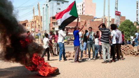 Sudanese demonstrators lift national flags and burn tyres on a street in the capital Khartoum, on October 26, 2021, as they protest a military coup that overthrew the transition to civilian rule. - Angry Sudanese stood their ground in street protests against a coup, as international condemnation of the military&#39;s takeover poured in ahead of a UN Security Council meeting. (Photo by AFP) (Photo by -/AFP via Getty Images)
