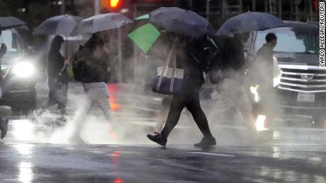 People with umbrellas walk in the rain and steam in New York City's Manhattan borough on Tuesday.