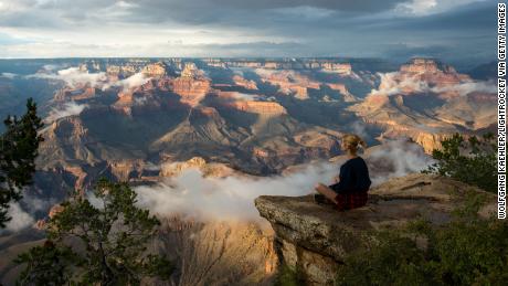 Une femme est assise près de Yavapai Point sur la rive sud surplombant le Grand Canyon, l'un des trois sites du patrimoine mondial des États-Unis qui, selon l'UNESCO, est devenu une source d'émissions de carbone.