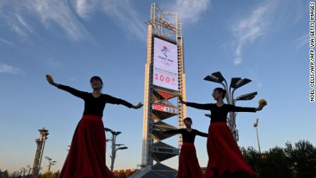 Dancers perform in front of the countdown clock showing 100 days until the opening of the 2022 Beijing Winter Olympics, at the Olympic Park in Beijing on October 27, 2021. (Photo by Noel Celis / AFP) (Photo by NOEL CELIS/AFP via Getty Images)