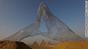 A view of the sculpture &#39;Together&#39; by Italian sculptor Lorenzo Quinn, son of late actor Anthony Quinn, is seen in front of the Great Pyramids of Giza, on the outskirt of Cairo, Egypt, October 23, 2021. Picture taken October 23, 2021. REUTERS/Mohamed Abd El Ghany TPX IMAGES OF THE DAY