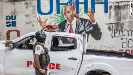 A police officer stands near a mural of the late Haitian President Jovenel Moïse, who was assassination in July 2021.