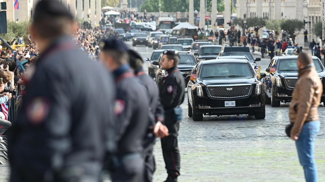 Police officers stand as Biden&#39;s motorcade drives by Friday en route to the Vatican.