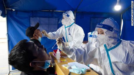 29 октября медицинский персонал берет образец мазка у мужчины для тестирования на коронавирус Covid-19 в районе Ганьчжоу города Чжанъе в провинции Ганьсу на северо-западе Китая.