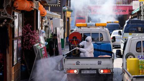 10月29日金曜日、韓国のソウルで、コロナウイルスに対する予防措置として、安全装備を身に着けた地元の保健官が店先を消毒しました。