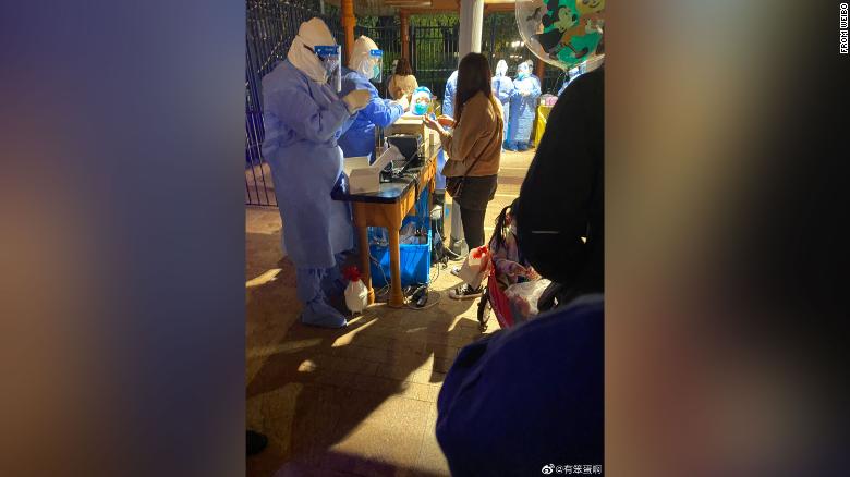 Shanghai Disneyland visitors queue for Covid-19 testing after the park announced a snap lockdown on Sunday.