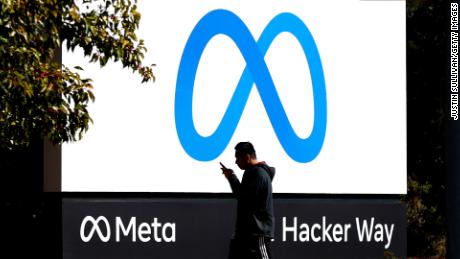 A pedestrian walks in front of a new logo and the name &#39;Meta&#39; on the sign in front of Facebook headquarters on October 28, 2021 in Menlo Park, California. A new name and logo were unveiled at Facebook headquarters after a much anticipated name change for the social media platform.