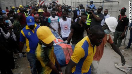 ナイジェリアラゴスで建設中の建物崩壊現場で救助隊員たちが遺体を移している。 