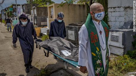 A  priest carries a body bag containing the remains of a victim of an alleged extrajudicial killing five years ago, which was exhumed after the lease on his tomb expired at a public cemetery on September 17 in Navotas, Metro Manila, Philippines.