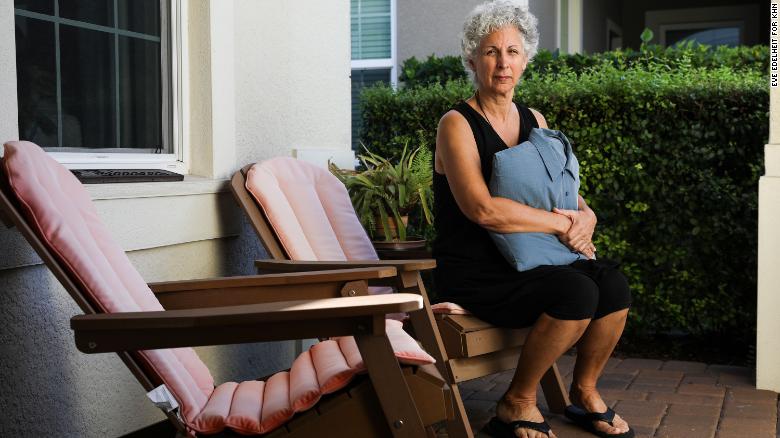 Cindy Johnson holds a pillow made from a shirt her husband, Steven, used to wear. Steven died of covid-19 in December 2020, and Cindy believes he contracted the virus at Blake Medical Center in Bradenton, Florida, where he was admitted for an infection in his hip. (Eve Edelheit for KHN)