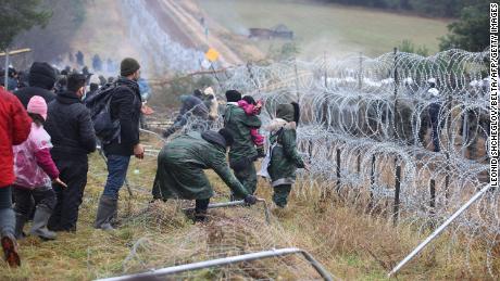 Migrants approach a barbed wire fence along the Belarusian-Polish border. 