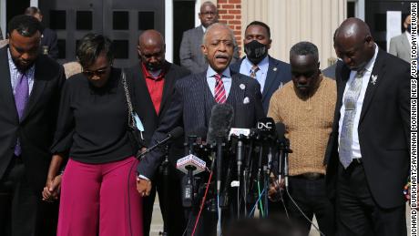 Rev. Al Sharpton, center, holds hands with Ahmaud Arbery&#39;s parents Wanda Cooper-Jones and Marcus Arbery as they pray together on Wednesday in front of the Glynn County Courthouse.