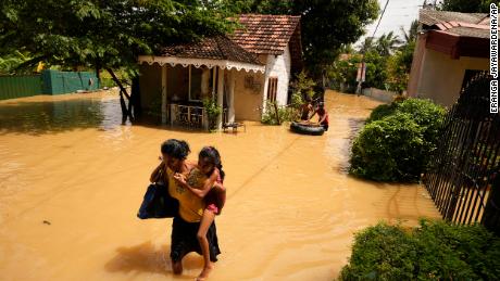A woman and child wade through a flooded area in Kochchikade,  Sri Lanka on November 10, 2021. 