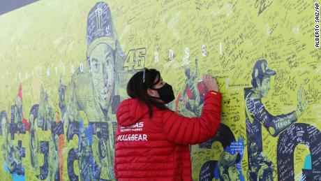 A fan writes a thank you message on a mural dedicated to Rossi before the Valencia GP.