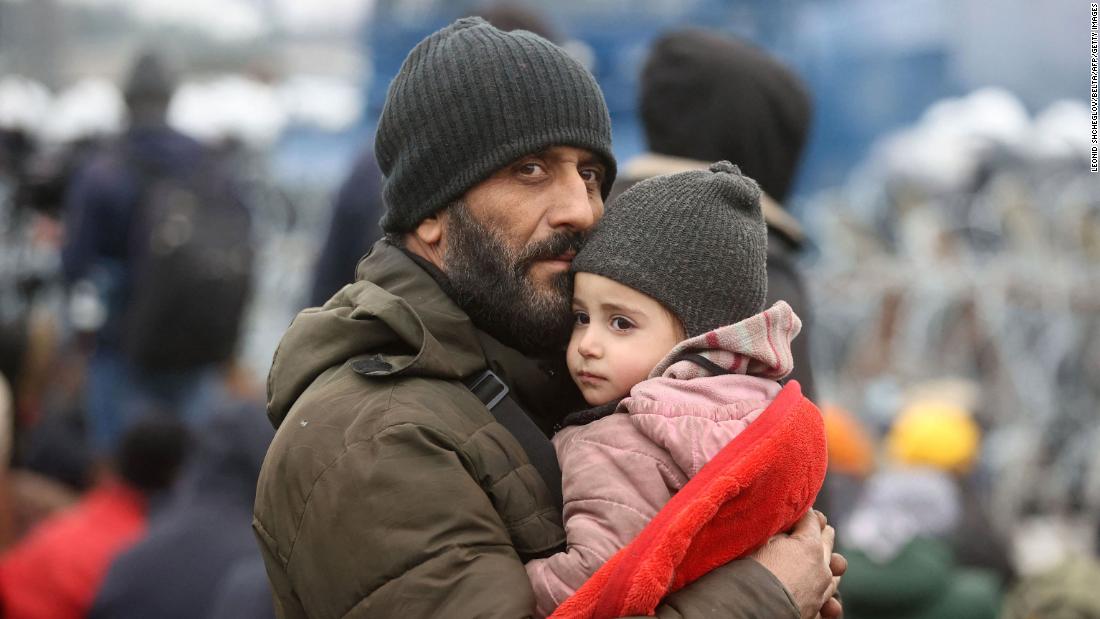 A man holds a child at the Bruzgi-Kuznica border crossing on Monday, November 15.
