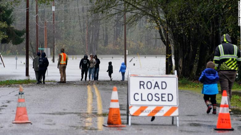 People in Sedro-Woolley, Washington, walk up to a roadway flooded Monday by the overflowing Skagit River.