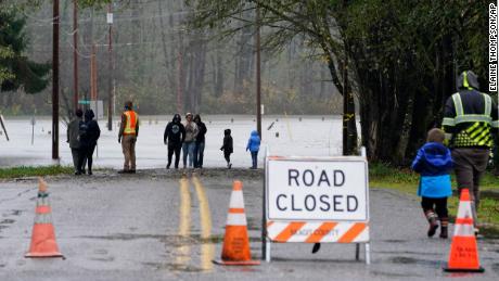 ワシントン州セドロ・ウーリーで人々は月曜日に氾濫したスカジット川に氾濫した道路に歩いています。