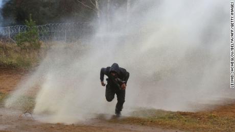 A man flees from a water cannon fired by Polish officers at the Bruzgi-Kuźnica border post.