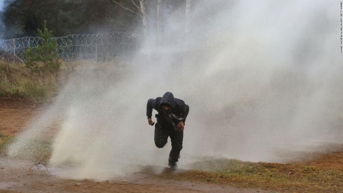 A man runs from a water cannon used by Polish border guards on Tuesday, November 16.