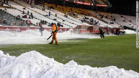 Personeel maakt de sneeuw van het veld schoon voor de wedstrijd in Edmonton.