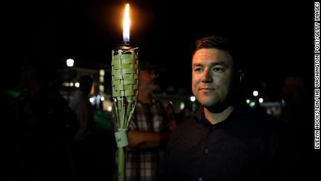 Jason Kessler, the organizer of Unite the Right, stands beside a torch before the march the night ahead of the rally.
