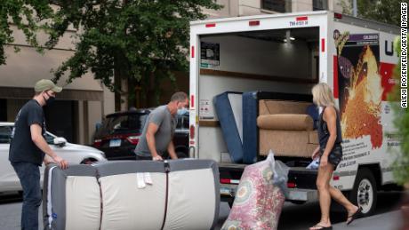People wearing masks load furniture into a U-haul moving truck as the city continues Phase 4 of re-opening following restrictions imposed to slow the spread of coronavirus on September 12, 2020, in New York City. 