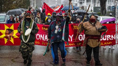 PLYMOUTH, MA - NOVEMBER 26: Demonstrators march through rain in Plymouth while participating in the 50th Anniversary of The National Day of Mourning, a reminder of the genocide of millions of Native people and the theft of Native lands , in Plymouth, MA on Nov. 26, 2020. For the past 50 years Native Americans and supporters gather at noon on Coles Hill overlooking Plymouth Harbor to commemorate a National Day of Mourning on the US thanksgiving holiday. (Photo by Erin Clark/The Boston Globe via Getty Images)