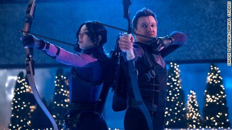 Haley Steinfeld as Kate Bishop (from left) and Jeremy Renner as Clint Barton / hockey star at Marvel Studios'  "Hockey." 