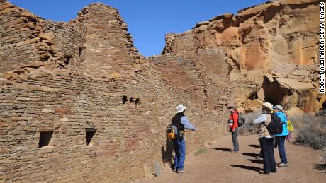 A guide leads a group of visitors through the ruins of a massive stone complex (Pueblo Bonito) at Chaco Culture National Historical Park in northwestern New Mexico. The communal stone buildings were built between the mid-800s and 1100 A.D.