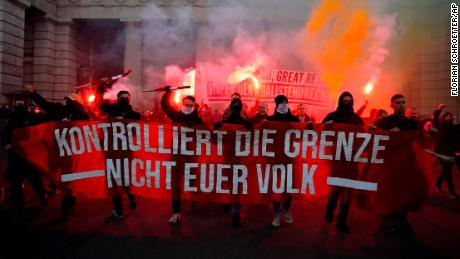 Crowds shout slogans and light flares during a demonstration against Austria&#39;s Covid restrictions. The banner reads: &quot;Control the border. Not your people.&quot;