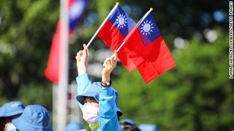 Seorang wanita memegang bendera Taiwan di depan Istana Kepresidenan sebelum perayaan Hari Nasional dimulai di Taipei, Taiwan, pada 10 Oktober 2021. 
