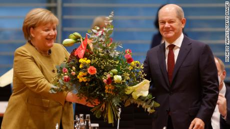 Acting Chancellor Angela Merkel receives a bouquet of flowers from acting Finance Minister Olaf Scholz during a cabinet meeting Wednesday.  