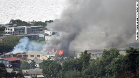 A fumaça subiu de prédios em Honolulu, nas Ilhas Salomão, em 25 de novembro, a capital foi incendiada no segundo dia dos distúrbios e ameaçou derrubar o governo do Pacífico. 