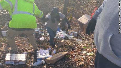 People work to collect packages thrown into an Alabama ravine.