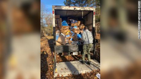 Hundreds of packages thrown into an Alabama ravine are loaded onto a truck Thursday, November 25, 2021. 