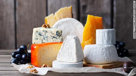 Cheese assortment: blue cheese, hard cheese, soft cheese on a parchment paper. Wooden background. Copy space.
