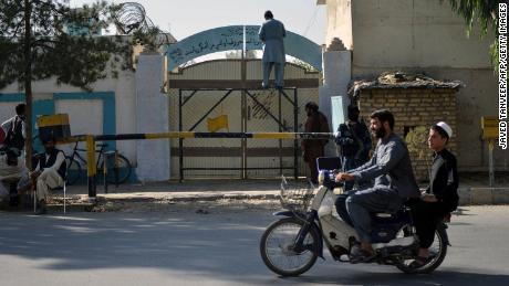 A Taliban replaces a sign of the Department for Women's Affairs with the Ministry for the Promotion of Virtue and Prevention of Vice, at an entrance gate of a government building in Kandahar on October 20.