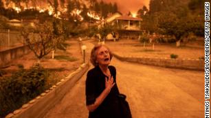 August 8: A woman reacts as a wildfire approaches her house in the village of Gouves, on the island of Evia, Greece. Thousands of residents were forced to flee Evia, which is about 100 miles north of Athens. 