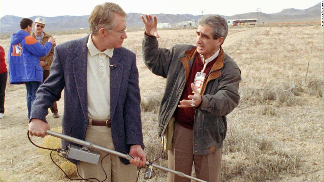 Reid, holding a land-mine detection device, listens as scientist Gregory Pekarsky explains how it works during a demonstration in Mercury, Nevada, in 1998.