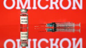 An illustration picture taken in London on December 2, 2021 shows a vial with Covid-19 vaccine sticker attached, beside syringes and a screen displaying the word &#39;Omicron&#39;,  the name of the new covid 19 variant. (Photo by Justin TALLIS / AFP) (Photo by JUSTIN TALLIS/AFP via Getty Images)