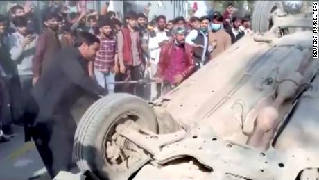 A mob hits an overturned car with sticks after an attack on a factory in Sialkot, Pakistan December 3, 2021, in this screen grab taken from a video.   Reuters TV via REUTERS  THIS IMAGE HAS BEEN SUPPLIED BY A THIRD PARTY.

