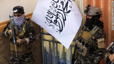 Taliban fighters stand guard next to a Taliban flag during a gathering where Afghan Hazara elders pledged their support to the country&#39;s new Taliban rulers, in Kabul on November 25, 2021.